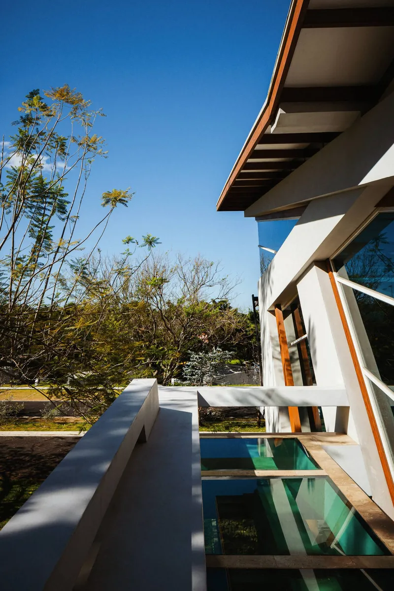 Alianz Loft, a faceted-glass structure standing among gardens and cypress trees by day at Nebulae