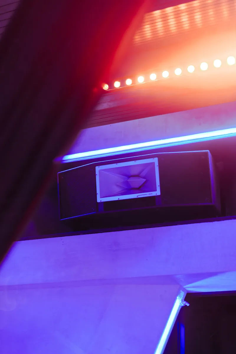 A Funktion-One loudspeaker integrated into the concrete architecture, lit in warm and blue light